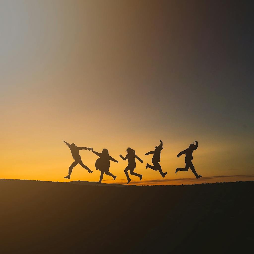 Group of friends jumping joyfully during sunset in Iceland, symbolizing freedom and happiness.